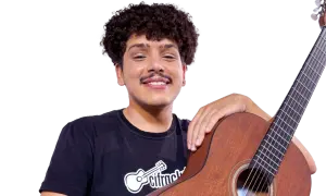 Uśmiechnięty chłopak z kręconymi włosami i gitarą. Zawsze z tobą chciałbym być, grając melodie.