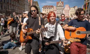 Młodzi muzycy grają na gitarach na rynku, jakby to był wieczór, gdy się poznali.