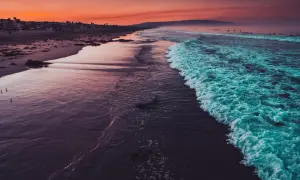 Zachód słońca nad oceanem, fale tańczą na piasku. Ona lubiła tańczyć tekst, gdy słońce malowało niebo na pomarańczowo.