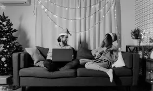Wśród nocnej ciszy chwyty ukulele i śmiech przy laptopie. Para w czapkach Mikołaja cieszy się świąteczną atmosferą.