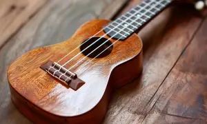 Drewniane ukulele na rustykalnym blacie. Idealne do nauki akordów "Can't Help Falling in Love".