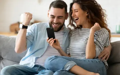 Para jak z liceum, zakochani, cieszą się z sukcesu, patrząc na telefon.