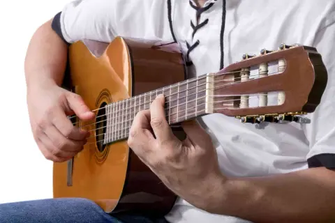 Ręce grające na gitarze klasycznej. Idealne, by zastanowić się, co zagrać na gitarze.