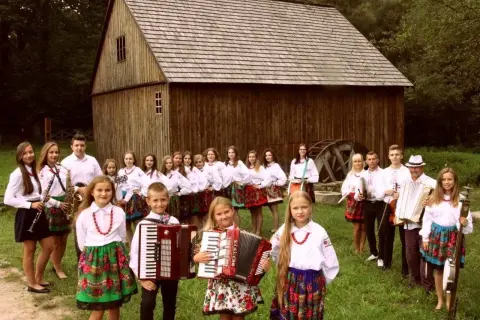 Guzowianki w ludowych strojach, z akordeonami i instrumentami, gotowe do występu.