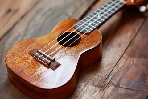 Drewniane ukulele na rustykalnym blacie. Idealne do nauki akordów "Can't Help Falling in Love".