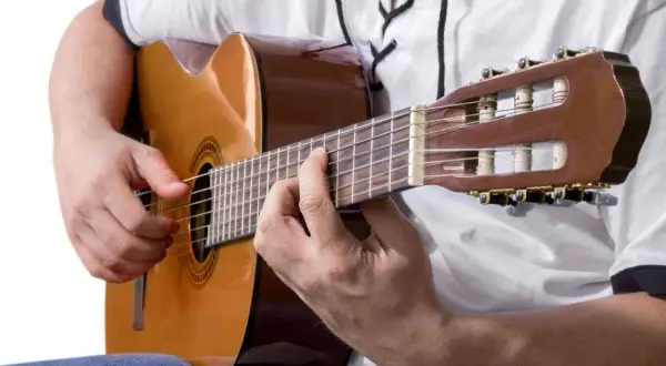 Ręce grające na gitarze klasycznej. Idealne, by zastanowić się, co zagrać na gitarze.