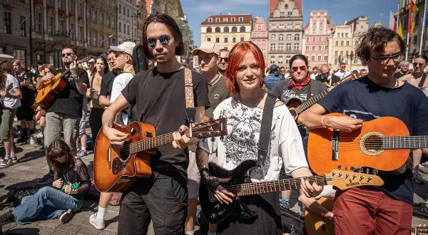 Młodzi muzycy grają na gitarach na rynku, jakby to był wieczór, gdy się poznali.