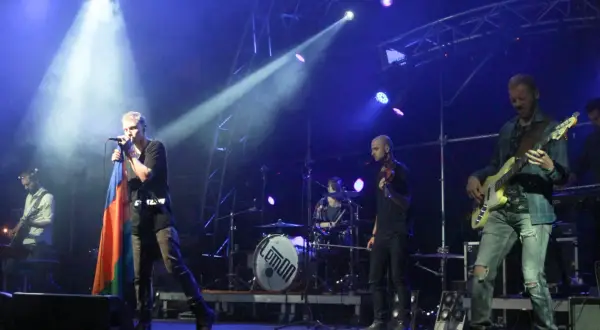 Zespół Lemon na scenie, wokalista z flagą, gitarzysta basowy, perkusja z logo.