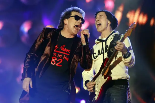 Na koncercie Lady Pank, wokalista w czarnej koszulce z napisem "Pank '82" i narzeczona w białej bluzie grają na gitarze.