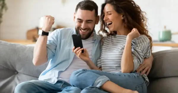 Para jak z liceum, zakochani, cieszą się z sukcesu, patrząc na telefon.
