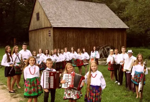 Guzowianki w ludowych strojach, z akordeonami i instrumentami, gotowe do występu.