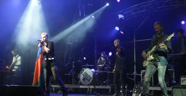 Zespół Lemon na scenie, wokalista z flagą, gitarzysta basowy, perkusja z logo.